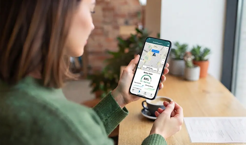 A woman in a café checks her mother's scooter on the MobilityGuard app.
